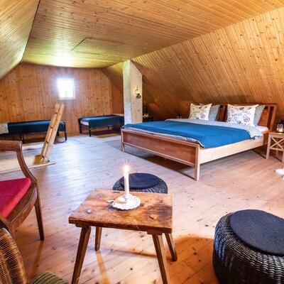 Das geräumige Dachgeschosszimmer im Hof ist mit Holzböden, Holzverkleidung an Wänden und Decke sowie einem Doppelbett und mehreren Einzel- und Tagesbetten ausgestattet.