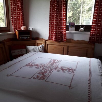 Schlafzimmer im Hof mit traditioneller Holzeckbank, einem Bett und Fenstern mit Blick ins Grüne.