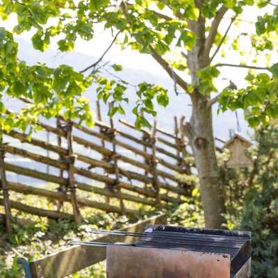 Grillbereich im Garten des Bed and Breakfast mit Sitzbank und Bergblick.