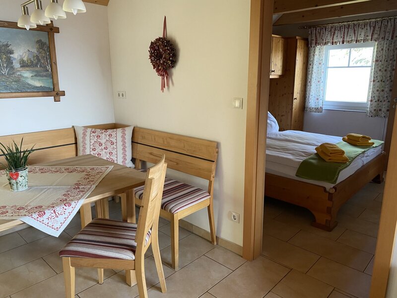 Essecke mit Vollholzmöbeln und angrenzendem Schlafzimmer mit Doppelbett im Bauernhof.