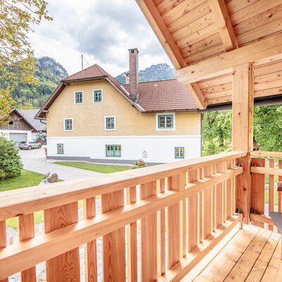 Holzbalkon des Bauernhofs mit Blick auf das Hauptgebäude und die umliegende Landschaft.