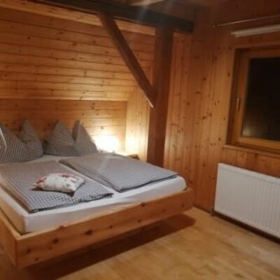 Doppelzimmer im Apartment mit Zirbenbett, Holzvertäfelung und Fenster.