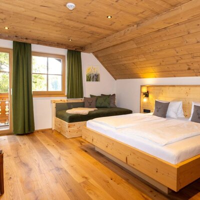 App. Wild & Wald - Schlafzimmer im Bauernhof mit Doppelbett, Tagesbett, Esstisch, Flat-TV und Balkon mit Bergblick. (c) Hans-Peter Steiner