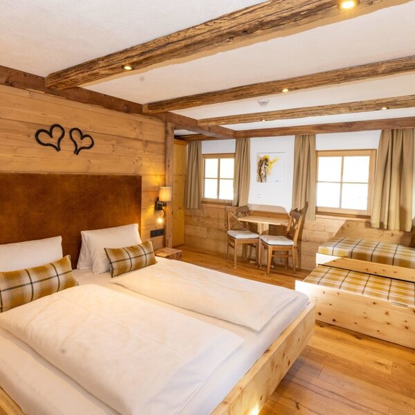 App. Pferdestall - Schlafzimmer im Bauernhof mit Doppelbett, Tagesbett, Holzeinrichtung und einem kleinen Tisch mit Stühlen. (c) Hans-Peter Steiner