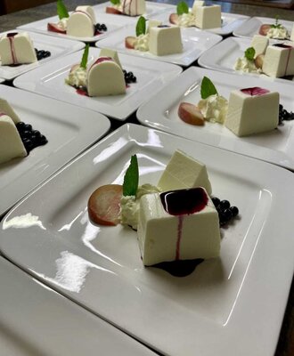 Dessertteller mit Holunderblütenmousse, Beerensauce, frischen Beeren, Fruchtscheiben und Minze, serviert im Bauernhof.