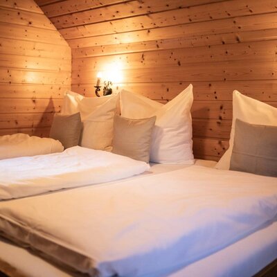 Schlafzimmer im Troadkasten mit Familienbett, Holzvertäfelung und Wandlampen.
