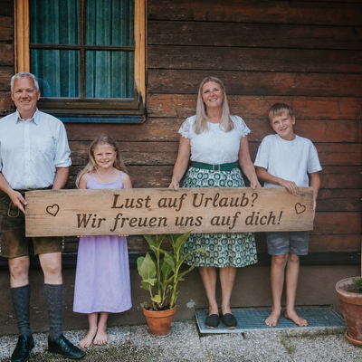 Die Gastgeberfamilie des Troadkasten mit einem Willkommensschild vor dem Gebäude.