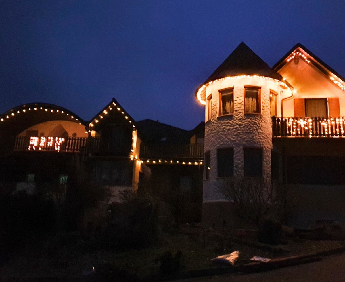 Außenansicht des Bauernhofs bei Nacht, geschmückt mit Lichterketten an den Balkonen und der Fassade.