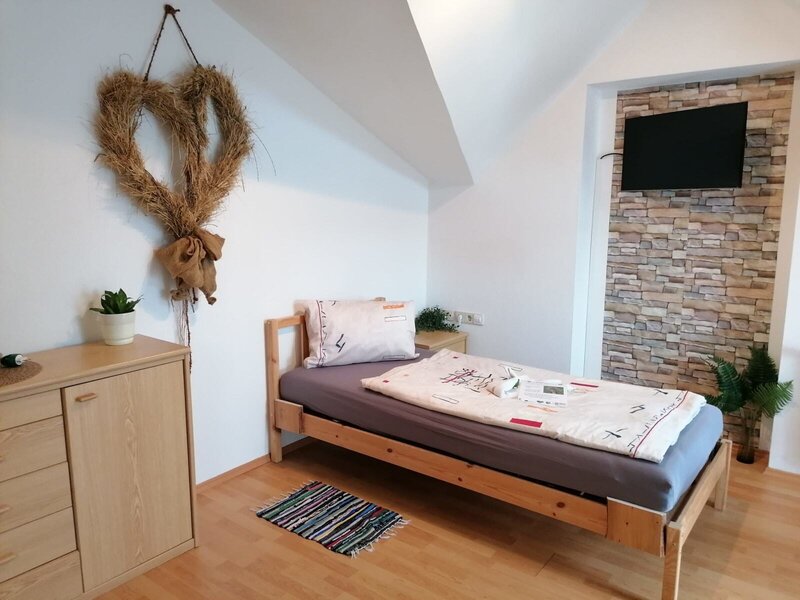 Einzelzimmer im Bauernhof mit Holzbett, Kleiderschrank und Wand-TV.