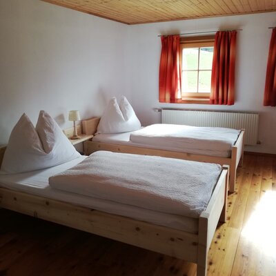 Schlafzimmer im Hof mit zwei Einzelbetten, Holzfußboden und Fenster.