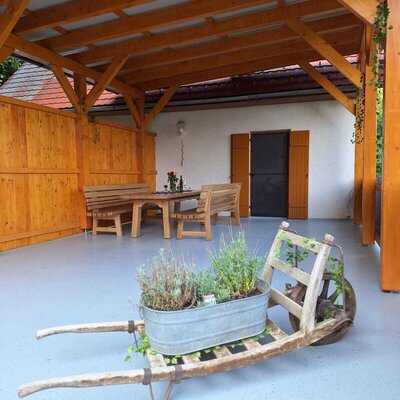 Überdachte Sitzgelegenheit am Bauernhof mit Holztisch und Bänken für Gäste.