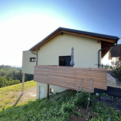 Der Hof mit einer Holzterrasse und Sonnenschirm bietet einen weiten Blick über die grüne Landschaft.