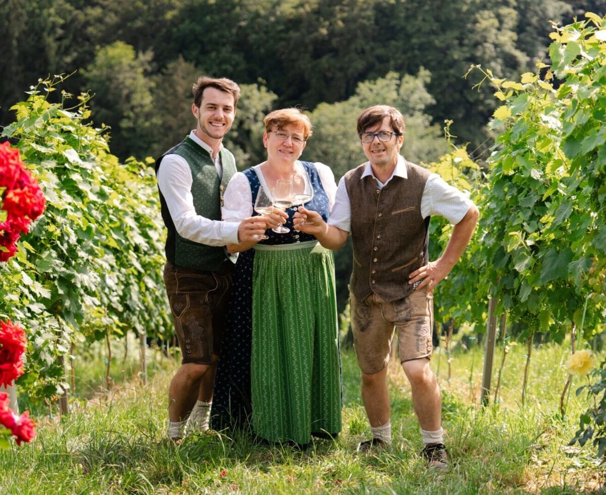 Die Gastgeber des Hauses in einem Weinberg mit Weingläsern.