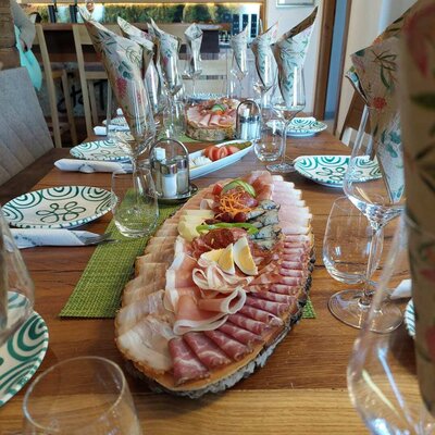 Der gedeckte Esstisch im Haus mit einer großen Aufschnittplatte, die Wurst, Käse, Eier und Gemüse umfasst.