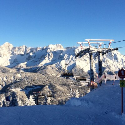 Skigebiet mit Sessellift und schneebedeckten Bergen.