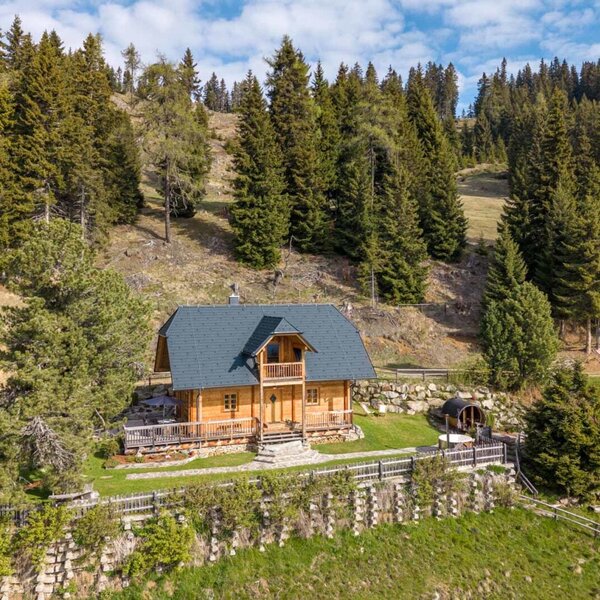 Außenansicht des Bed and Breakfast, ein Holzhaus mit Terrasse und Fasssauna, gelegen am Waldrand.