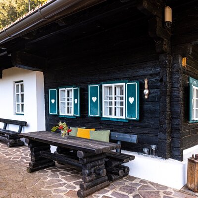 Die Steinterrasse des Winzerhauses mit Holztisch und Bänken bietet Gästen einen Außenbereich.