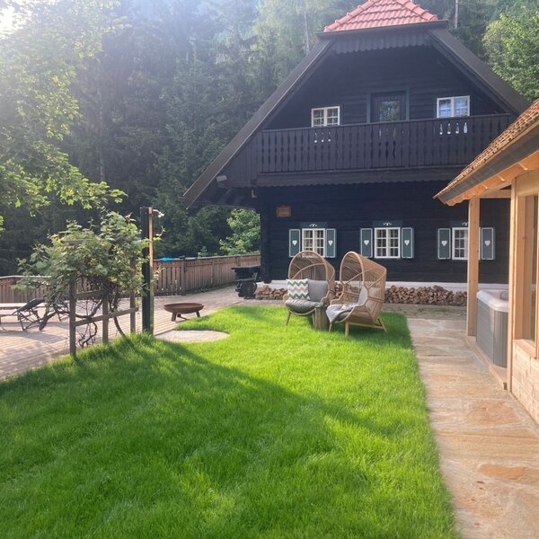 Außenbereich des Winzerhauses mit Rasen, Holzterrasse, Korbsesseln,  Whirlpool und Saunahaus.