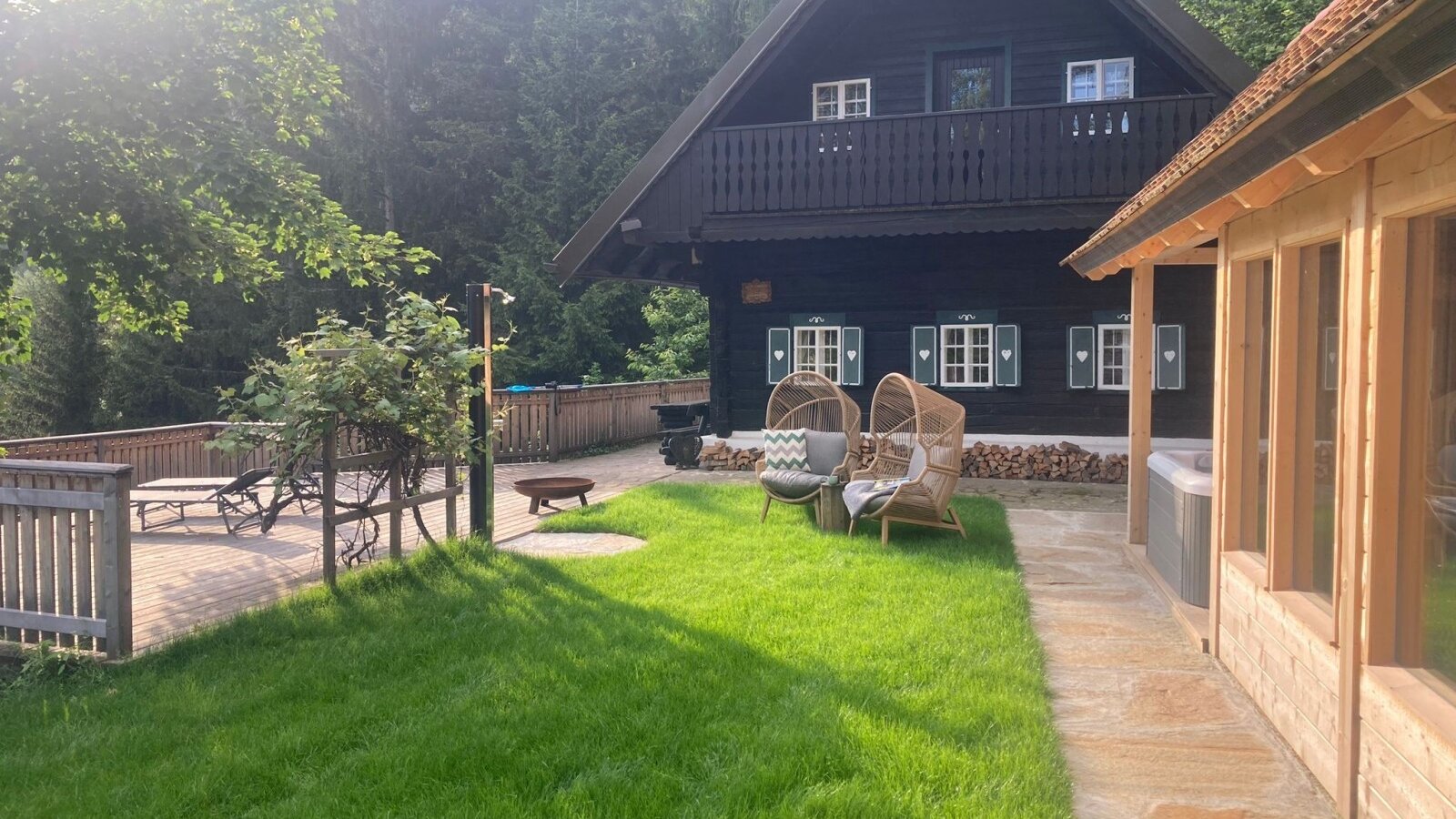Außenbereich des Winzerhauses mit Rasen, Holzterrasse, Korbsesseln,  Whirlpool und Saunahaus.