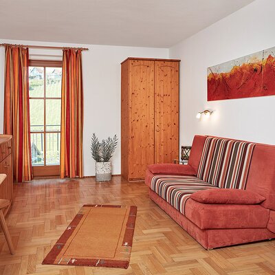 Ein Zimmer im Hof mit Schlafsofa, Essbereich, Fernseher und Zugang zum Balkon mit Blick auf die Weinberge.
