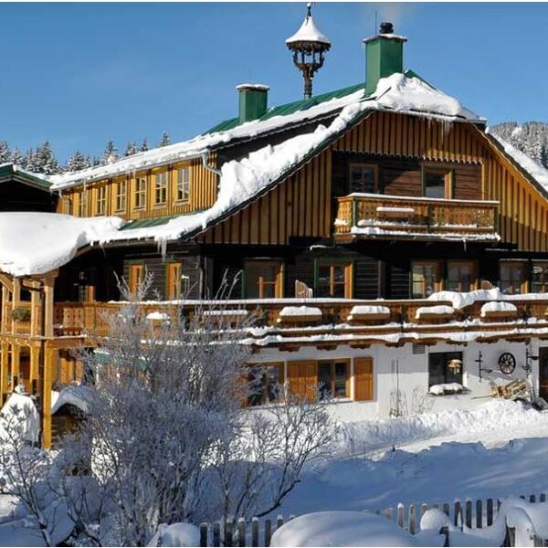 Der Bauernhof im Winter, mit schneebedeckten Dächern und Holzbalkonen.