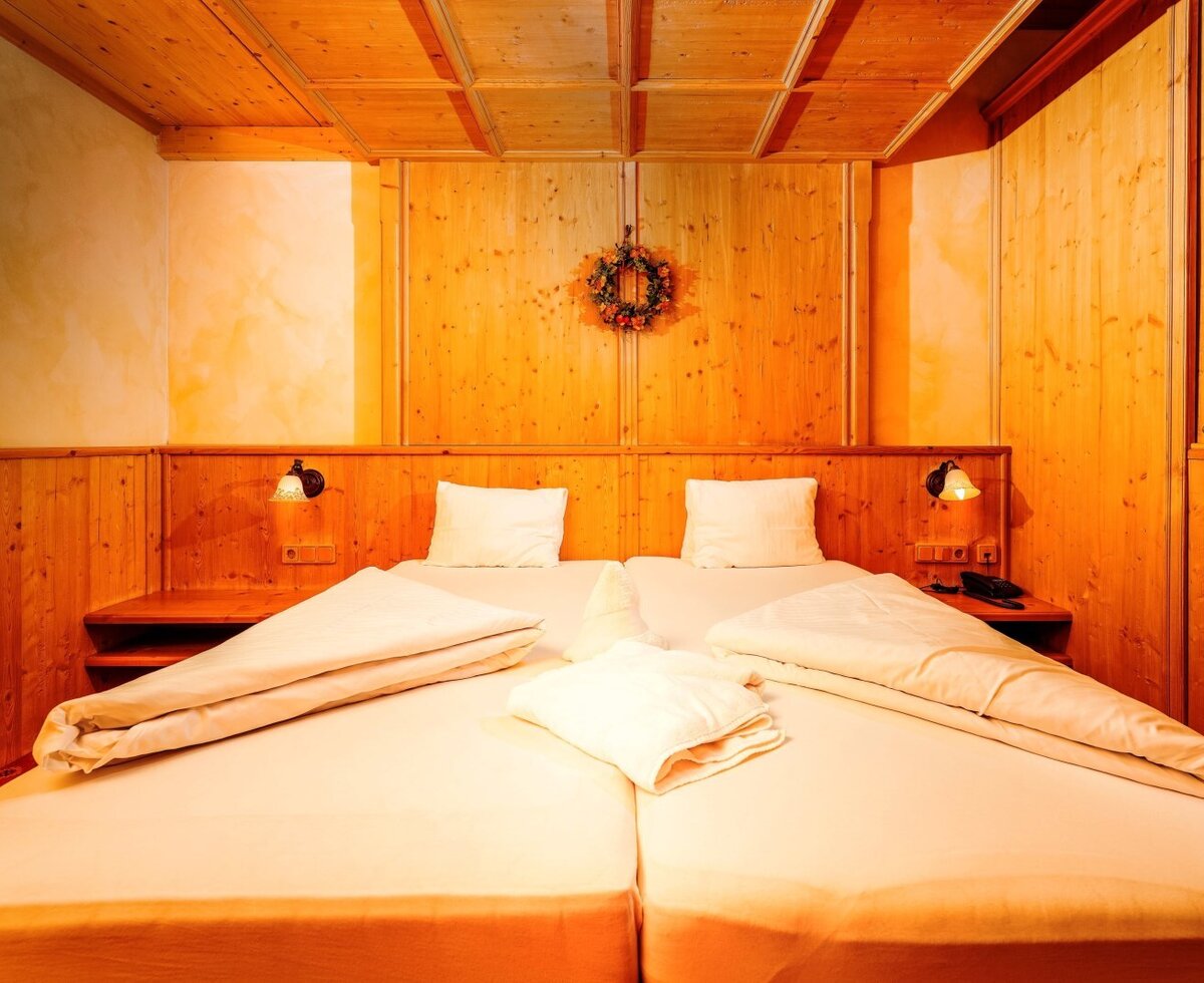 Behaglicher Schlafbereich der Suite Rosengarten im Haus Bergheimat mit warmem Holzdesign und modernem Komfort.