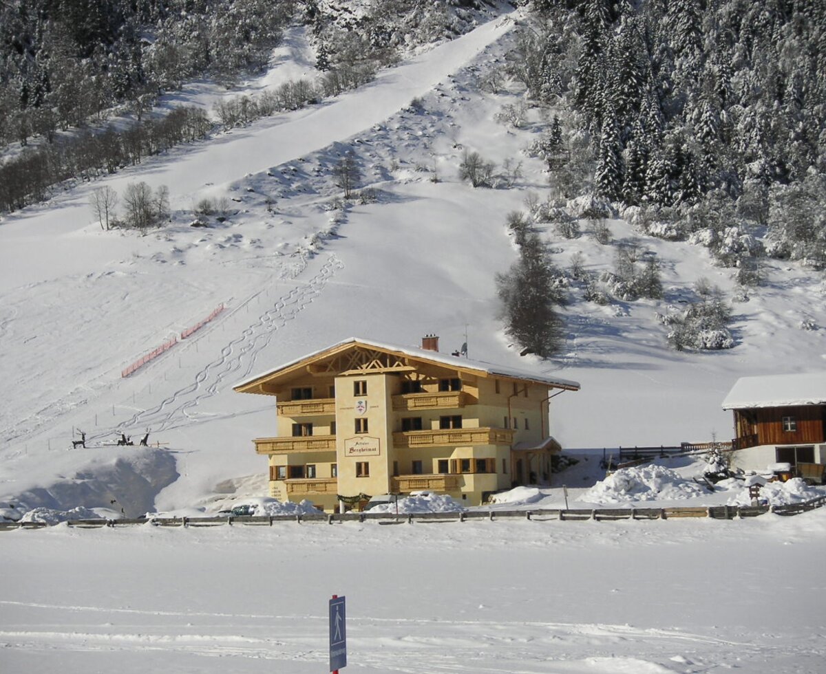 Winterliche Außenansicht der Bergheimat eingebettet in die verschneite Tiroler Berglandschaft.