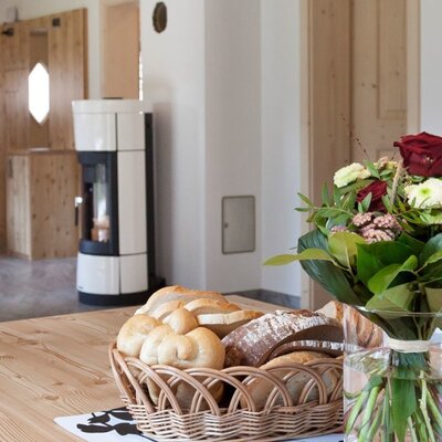 Der einladende Essbereich des Appartements mit einem rustikalen Holztisch, einem frischen Blumenstrauß und einem gemütlichen Kamin im Hintergrund.