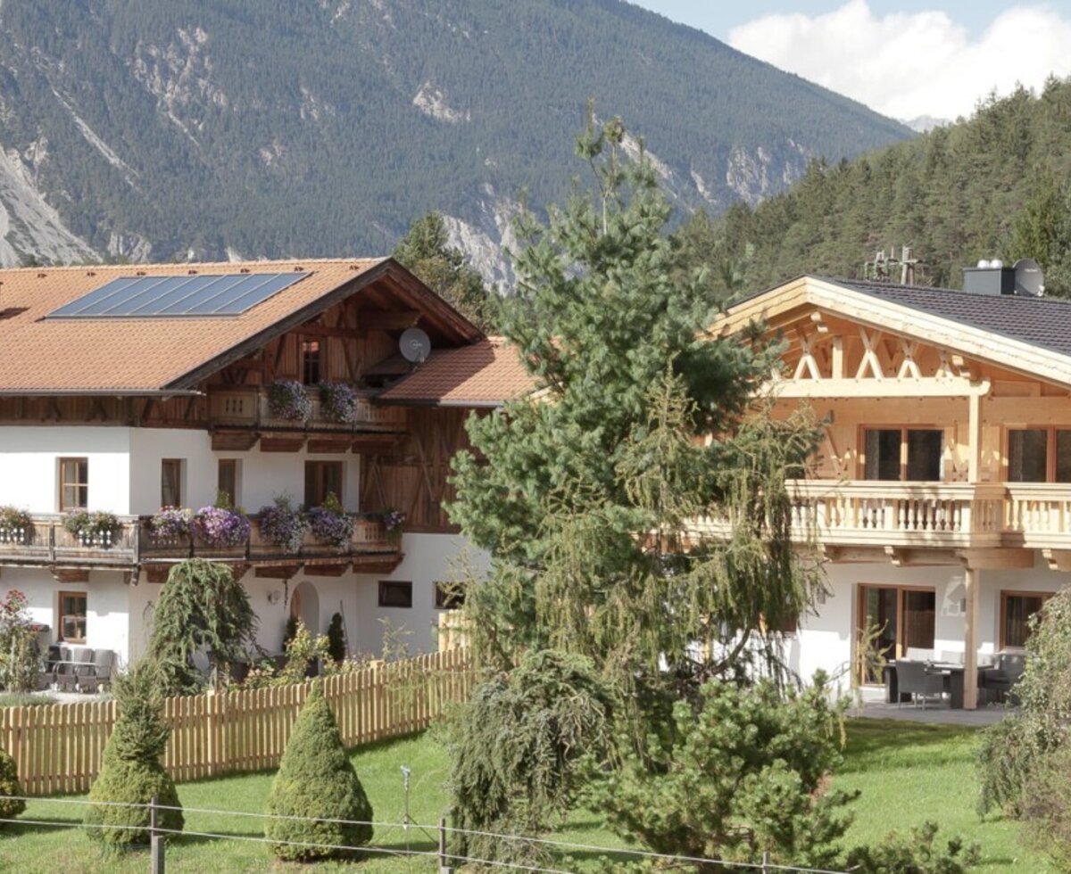 Die charmanten Appartements im traditionellen Alpendesign, umgeben von einem grünen Garten und einer malerischen Bergkulisse.