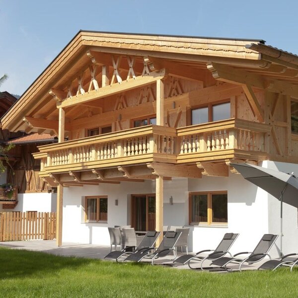 Die einladenden Appartements mit Holzfassade, sonniger Terrasse und gemütlichen Liegestühlen im grünen Garten.