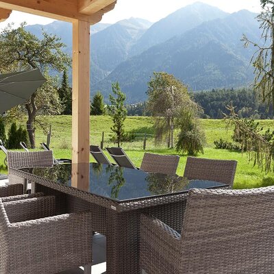 Einladende Terrasse des Appartements mit einer gemütlichen Sitzecke, Liegestühlen und einem herrlichen Blick auf die umliegenden Berge.