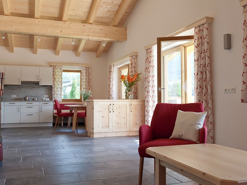 Ein geräumiges Appartement 2 mit hellem Holzgebälk, einer gemütlichen Kaminecke, einer modernen Küche und direktem Zugang zum Balkon.