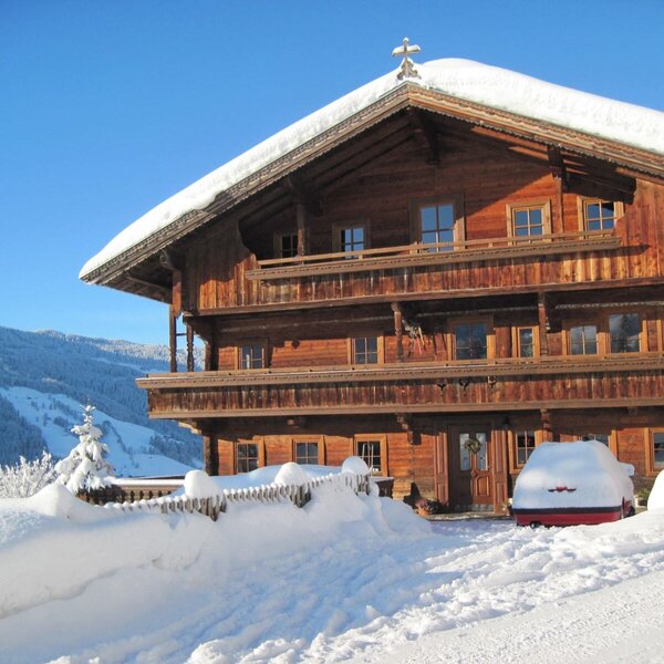 Der typische Alpbacher Bauernhof mit Holzfassade und Balkonen, umgeben von Schnee und Bergen.