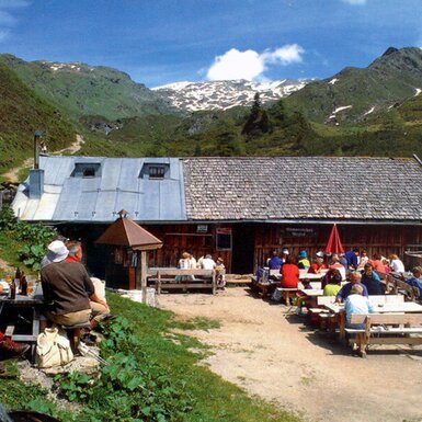 Die Alm bietet eine Außenterrasse mit Tischen für Verpflegung und Bergblick.