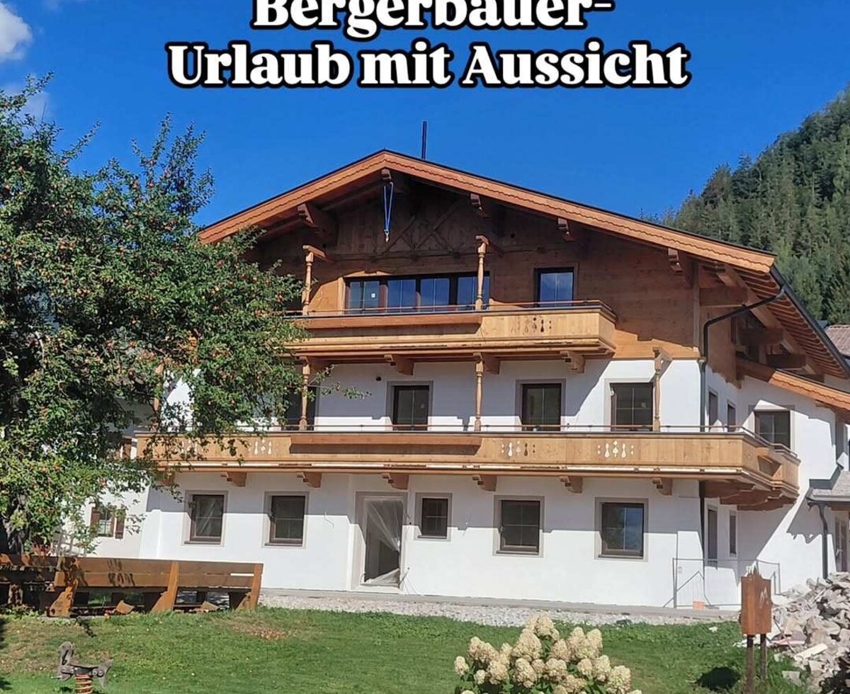 Das einladende Gebäude der Appartements im traditionellen Alpin-Stil mit Holzdetails und einer grünen Wiese davor.