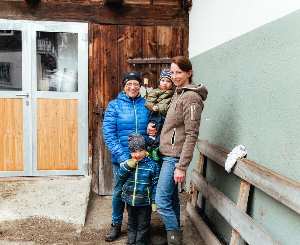 Die Gastgeberfamilie des Bauernhofs Bergerhof mit Kindern vor einem Hofgebäude.