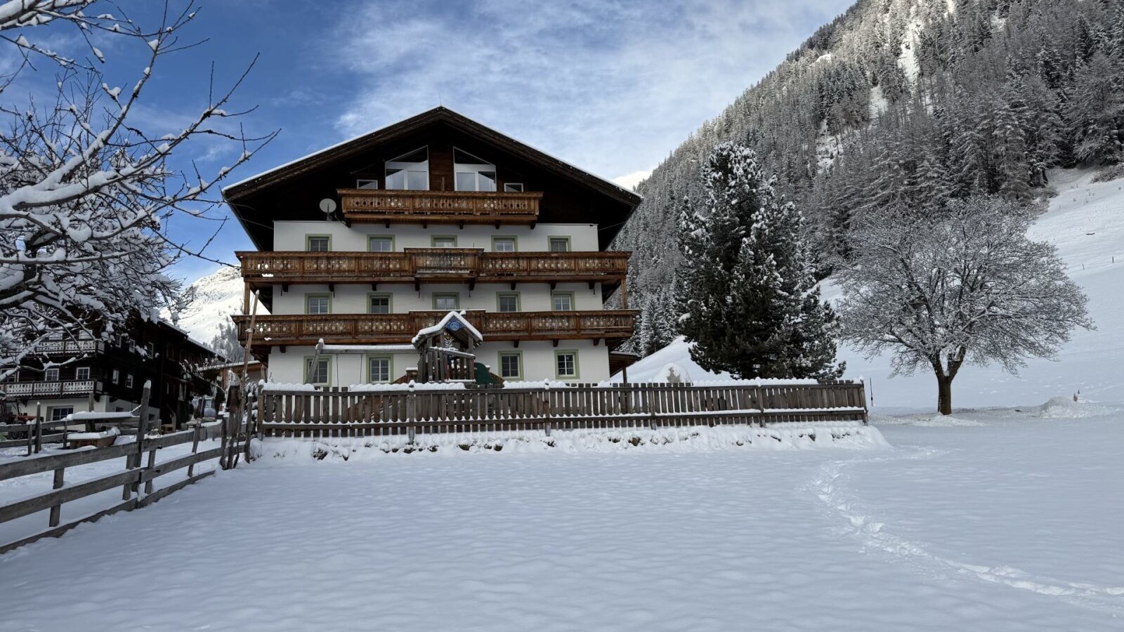 Der einladende Bauernhof umgeben von einer idyllischen, verschneiten Winterlandschaft und bewaldeten Berghängen.