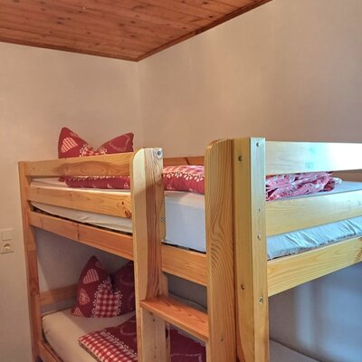 Etagenbett aus Holz mit rot-weiß gemusterter Bettwäsche in der Alm.