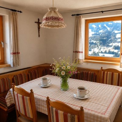 Gemütlicher Essbereich der Hütte mit einer traditionellen Eckbank aus Holz und malerischem Ausblick auf die verschneiten Berge.