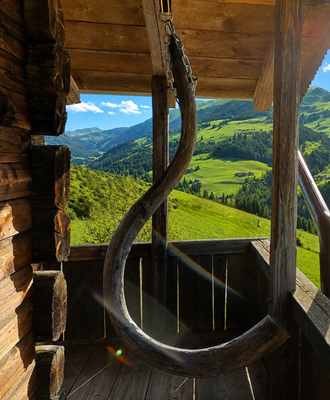 Der gemütliche Balkon der Alm mit einer urigen Holzschaukel und weitem Blick auf die grünen Berghänge.