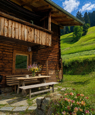 Ein gemütlicher Sitzbereich im Freien vor der urigen Alm, umgeben von saftig grünen Wiesen.