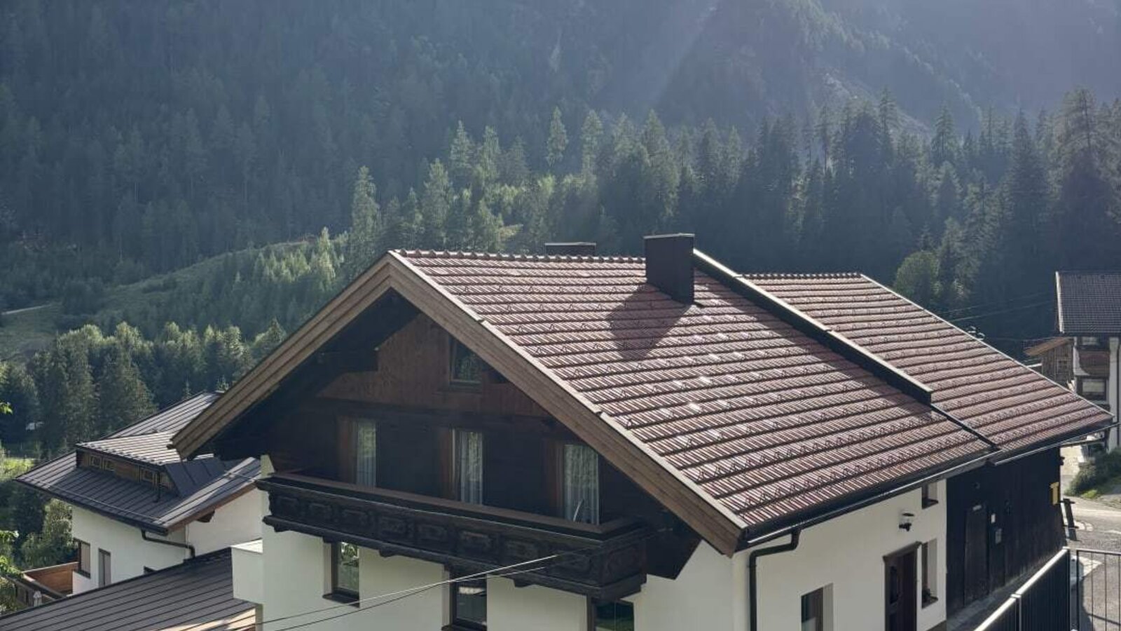 Das einladende Appartementhaus vor einer malerischen Bergkulisse mit einem kleinen Spielplatz im Garten.
