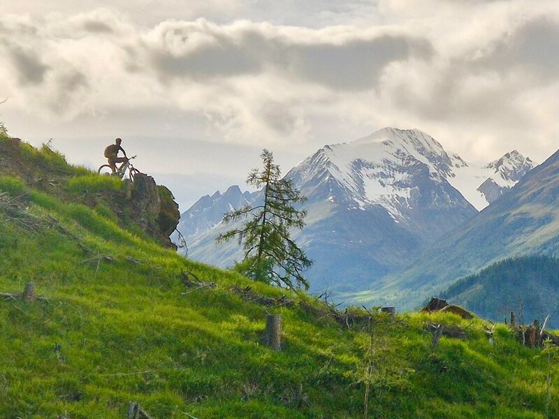Mountainbiker auf Felsvorsrprung und genießt die Aussicht und das Bergpanorama