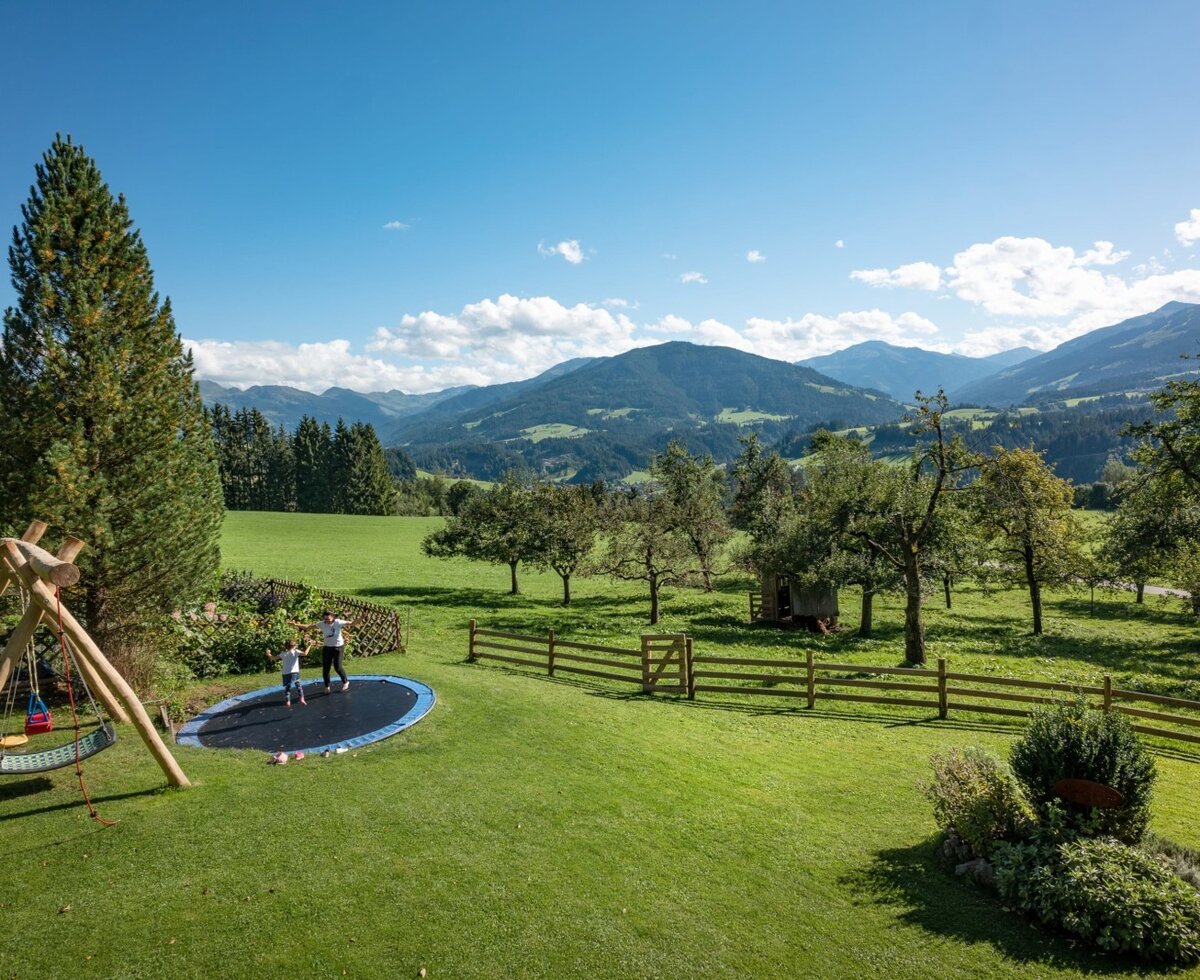 Aussicht auf den Garten mit unserem Trampolin und die umliegende Bergwelt