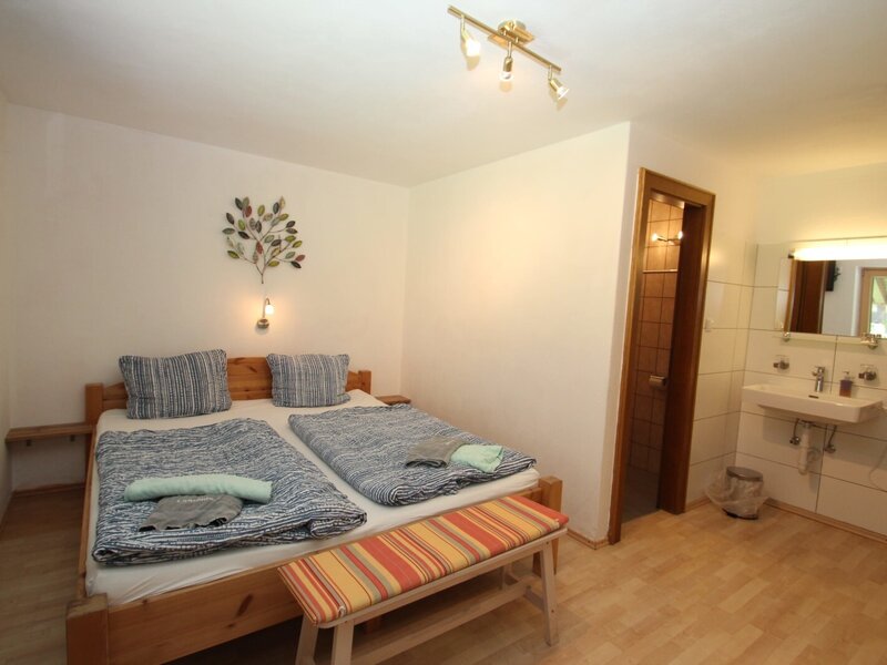 Schlafzimmer im Bauernhof mit Doppelbett, Fernseher, Waschbecken und Zugang zu DU/WC.