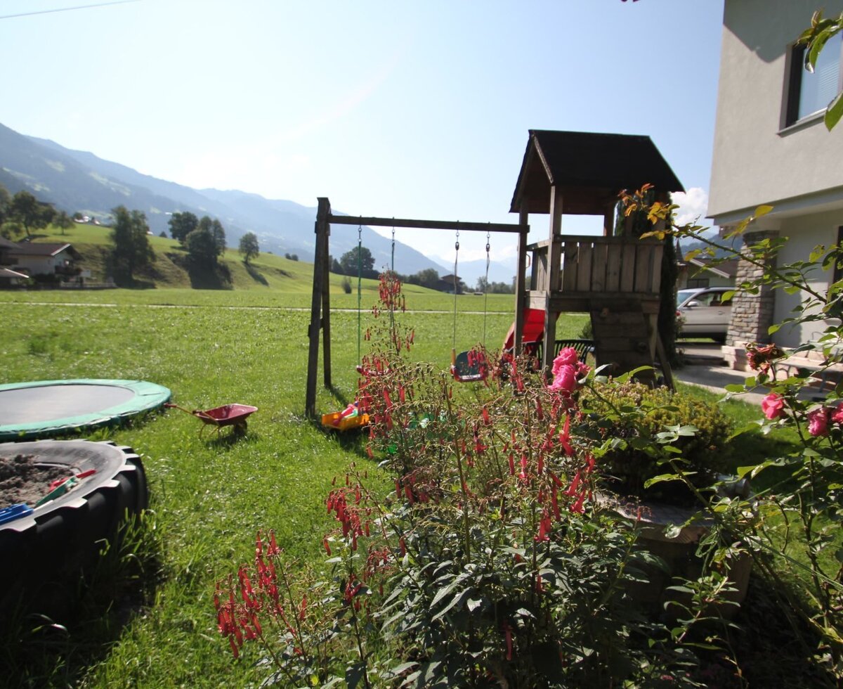 Der Spielplatz des Bauernhofs mit Schaukeln, Spielturm, Trampolin und Sandkasten.