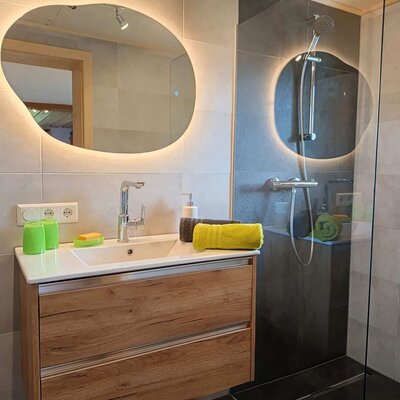Modernes Badezimmer im Bauernhof mit Waschtisch, beleuchtetem Spiegel und ebenerdiger Dusche.