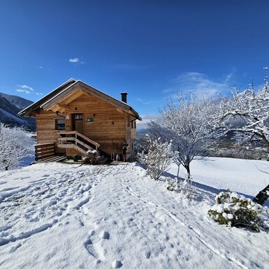 Das Ferienhaus am Hof in verschneiter Winterlandschaft mit Blick auf die umliegenden Berge.