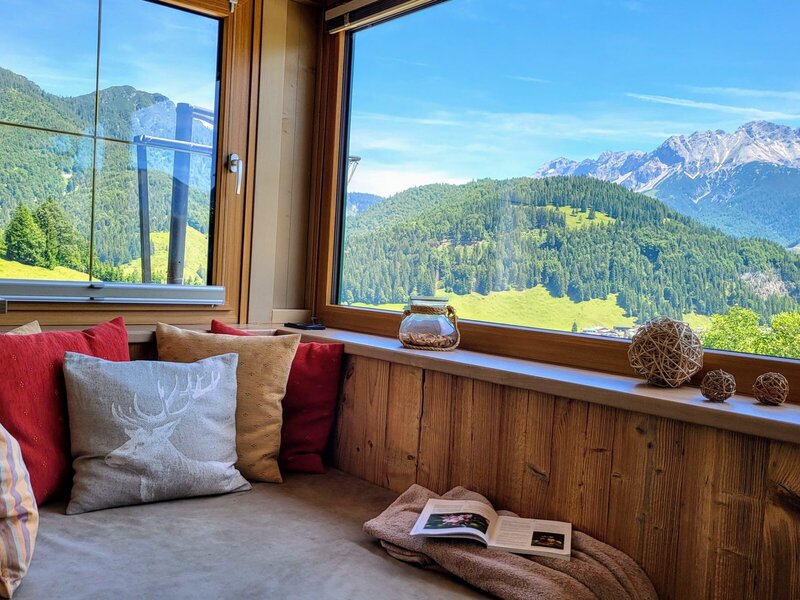 Sitzecke am Fenster mit Kissen und weitem Bergblick im Bauernhof.