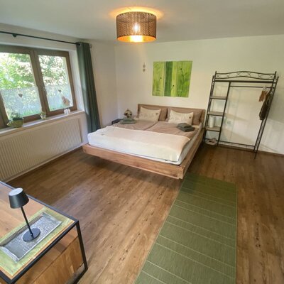 Ein gemütliches Schlafzimmer auf dem Bauernhof mit einem einladenden Doppelbett aus Holz, stilvollen Möbeln und warmen Farbakzenten.